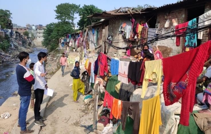 A survey team walks down a busy lane of homes