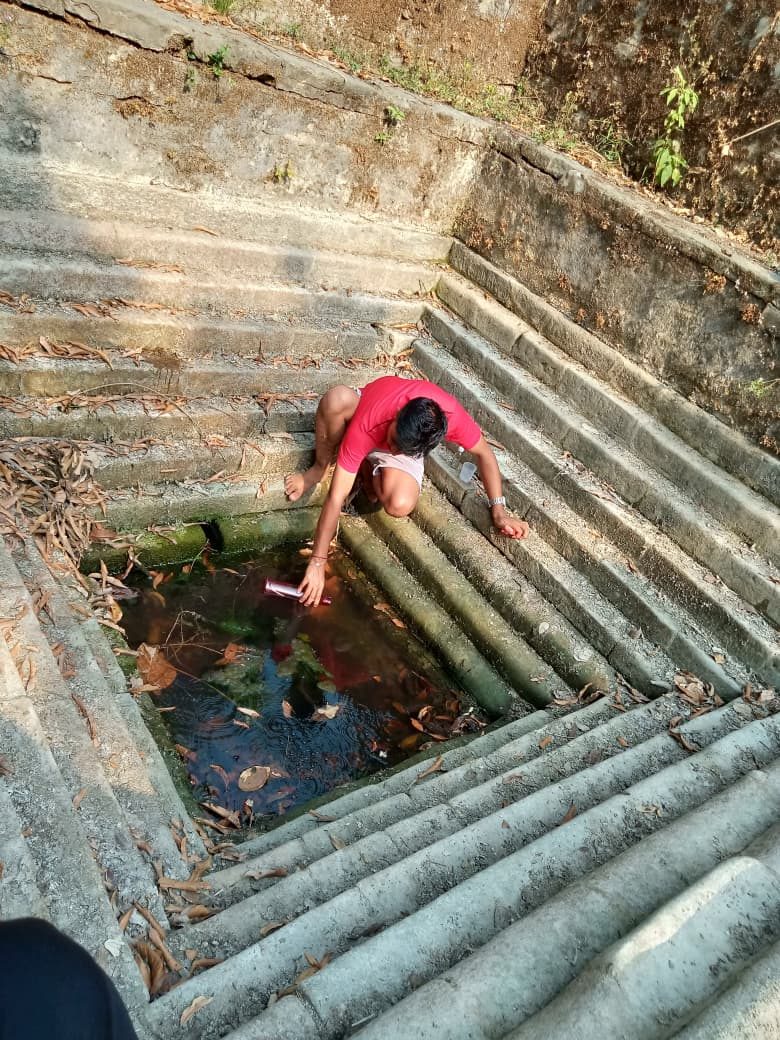 A woman draws water at a stone stepped spring